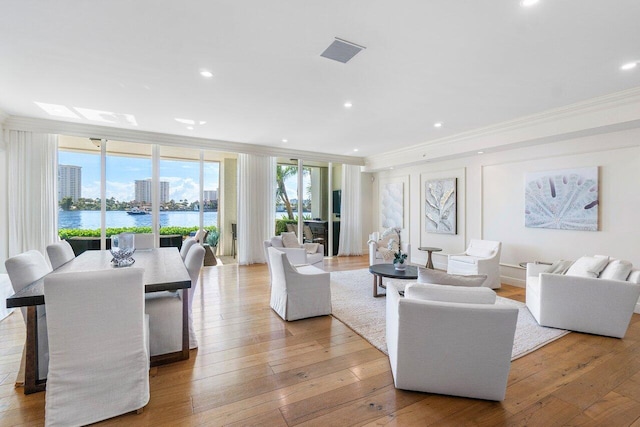 living room featuring floor to ceiling windows, light hardwood / wood-style flooring, a water view, and ornamental molding