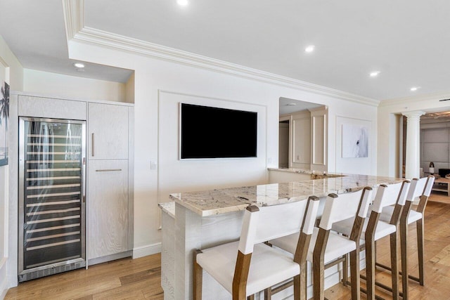 kitchen featuring light stone countertops, light wood-type flooring, beverage cooler, and ornamental molding