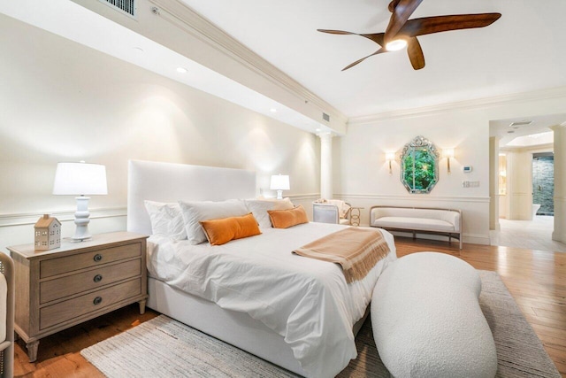 bedroom featuring ornate columns, ceiling fan, light hardwood / wood-style flooring, and ornamental molding