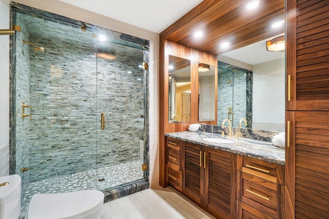 bathroom featuring vanity, toilet, and a shower with door