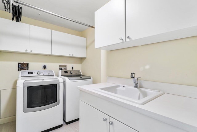 laundry area featuring cabinets, washer and clothes dryer, and sink