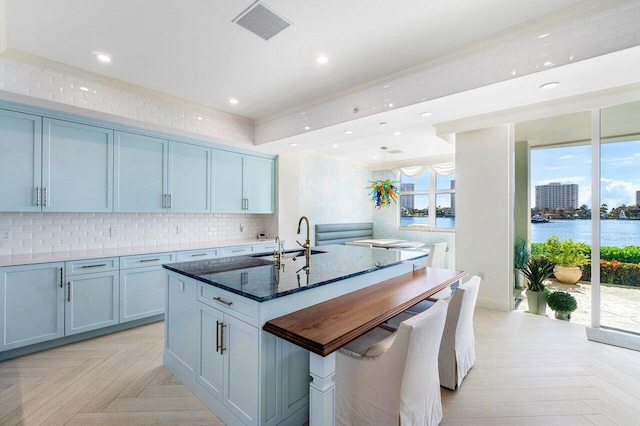 kitchen with a wealth of natural light, sink, a water view, and a center island with sink