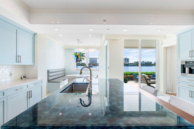 kitchen featuring decorative backsplash, dark stone counters, stainless steel oven, sink, and a water view