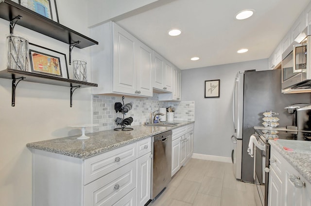 kitchen with white cabinets, appliances with stainless steel finishes, and light stone counters