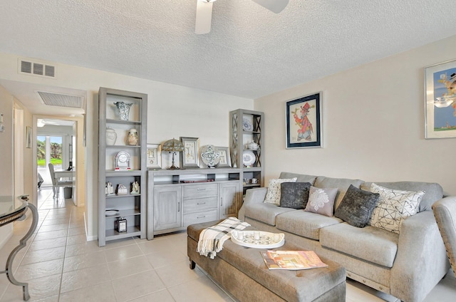 living room with ceiling fan, light tile patterned floors, and a textured ceiling