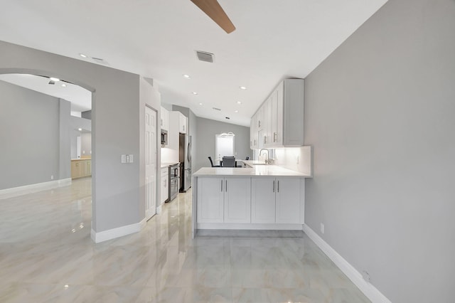 kitchen featuring kitchen peninsula, stainless steel refrigerator, sink, and white cabinets