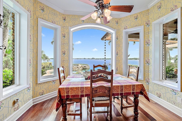 dining space with hardwood / wood-style floors, a water view, and crown molding