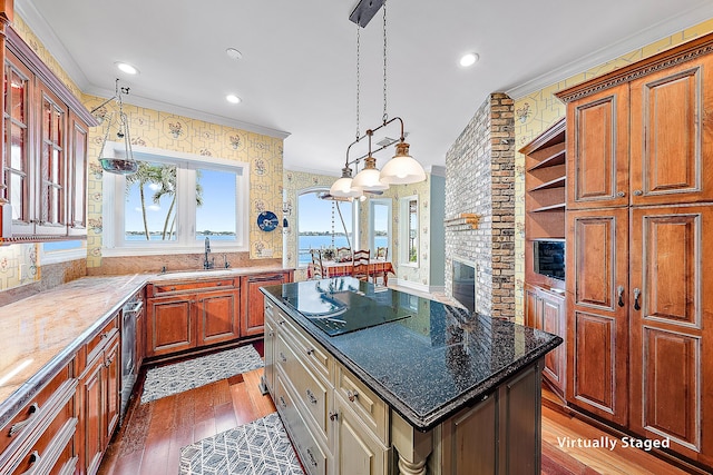 kitchen with a center island, dark stone counters, ornamental molding, and sink