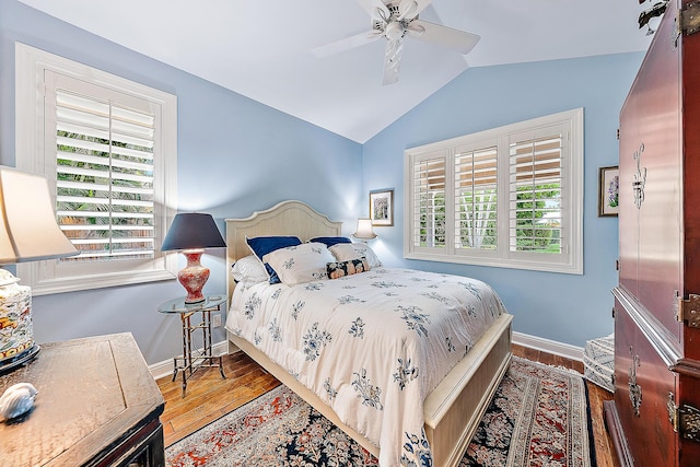 bedroom with hardwood / wood-style flooring, vaulted ceiling, multiple windows, and ceiling fan