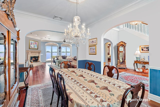 dining room with an inviting chandelier, a premium fireplace, dark wood-type flooring, and ornamental molding