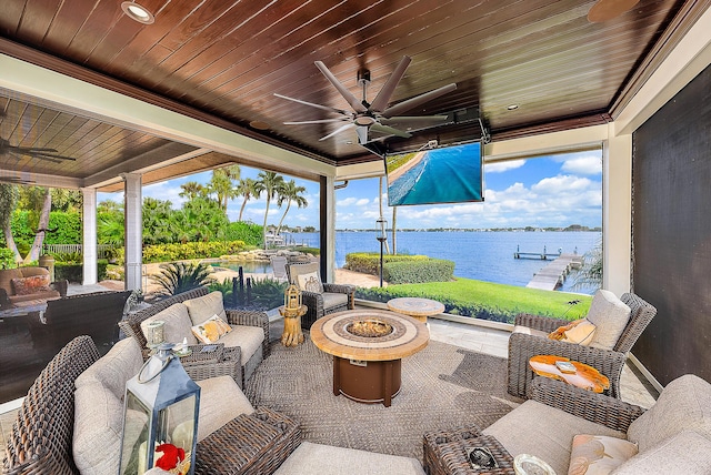 view of patio featuring a water view, ceiling fan, and an outdoor living space with a fire pit