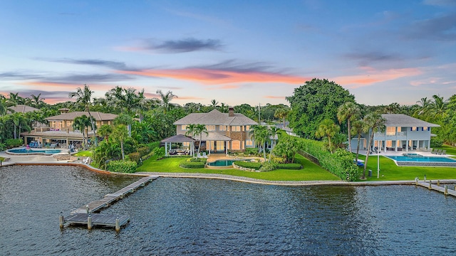 back house at dusk featuring a gazebo and a water view