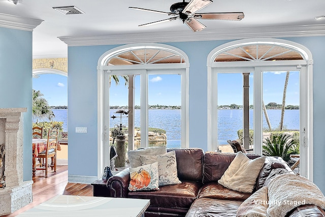 living room with ceiling fan, hardwood / wood-style floors, a water view, and ornamental molding