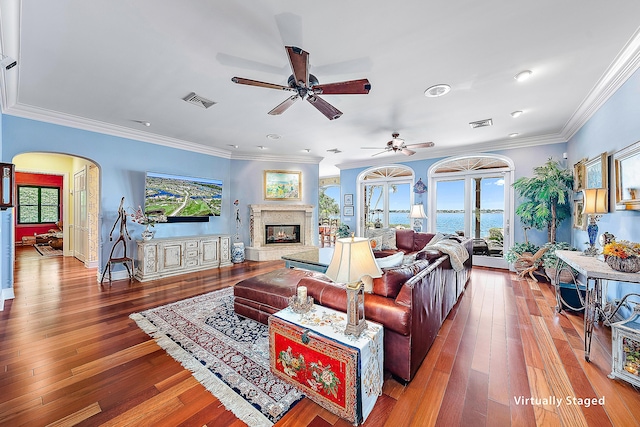 living room featuring a high end fireplace, hardwood / wood-style flooring, ceiling fan, and ornamental molding