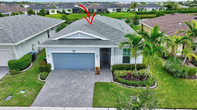 ranch-style house with a garage, a front lawn, and a water view