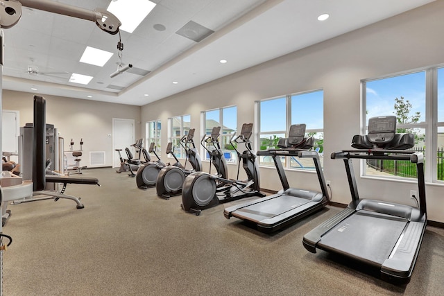 gym featuring a tray ceiling and a wealth of natural light