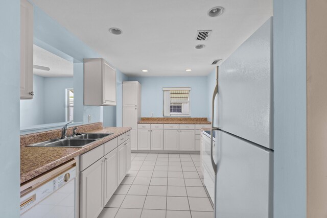 2078 SW 13th Ter, Boynton Beach, FL 33426 - kitchen with freestanding refrigerator, dishwasher, a sink, white cabinetry, and light tile patterned flooring