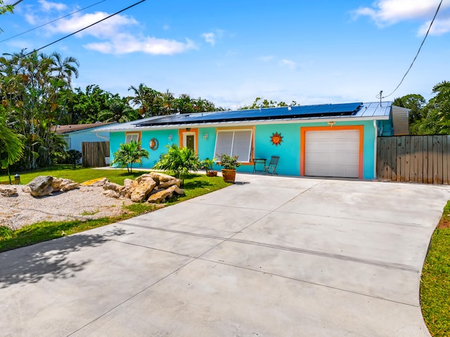 ranch-style home featuring a front yard, solar panels, and a garage