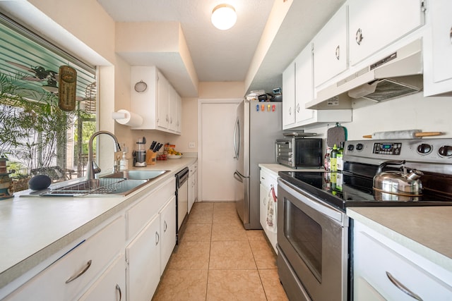 kitchen with white cabinets, appliances with stainless steel finishes, sink, light tile patterned flooring, and a textured ceiling