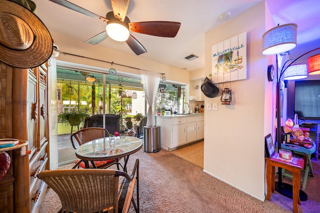 carpeted dining room featuring ceiling fan and sink