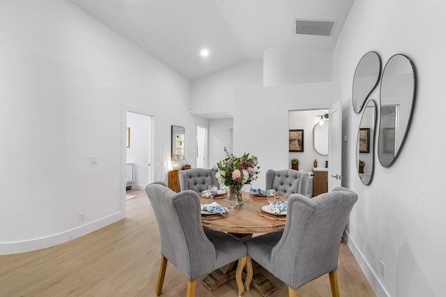 dining area featuring light hardwood / wood-style floors and high vaulted ceiling