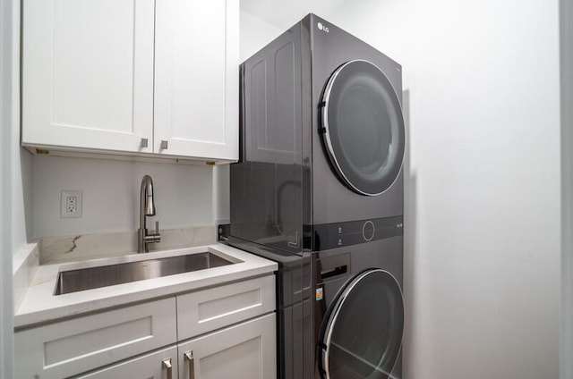 laundry room featuring stacked washer and clothes dryer, sink, and cabinets