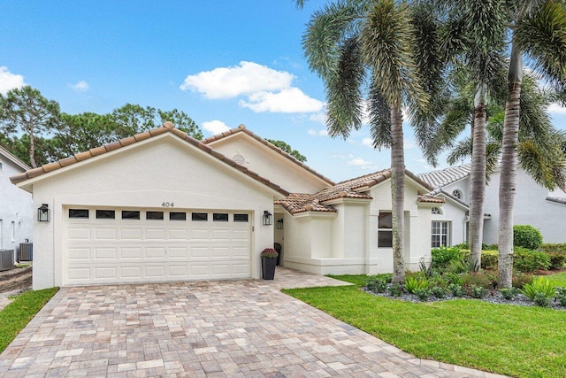 mediterranean / spanish house with a front yard, central air condition unit, and a garage