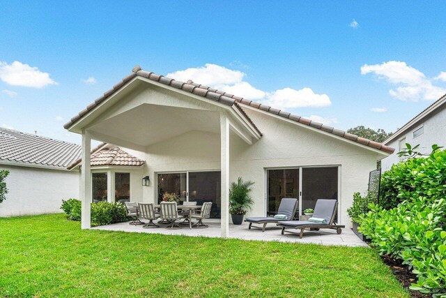 back of property featuring a patio and a yard