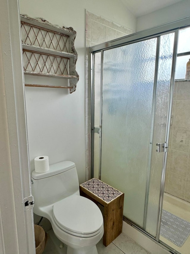 bathroom with tile patterned flooring, a shower with shower door, and toilet