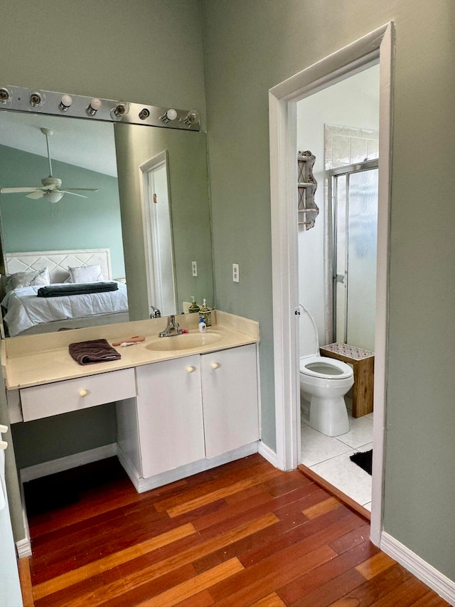 bathroom with vanity, ceiling fan, hardwood / wood-style flooring, a shower with door, and toilet