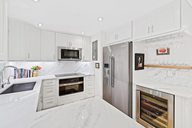 kitchen featuring beverage cooler, appliances with stainless steel finishes, white cabinetry, and sink