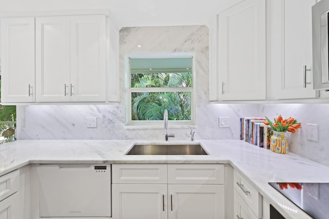 kitchen with white cabinets, light stone countertops, white dishwasher, and sink