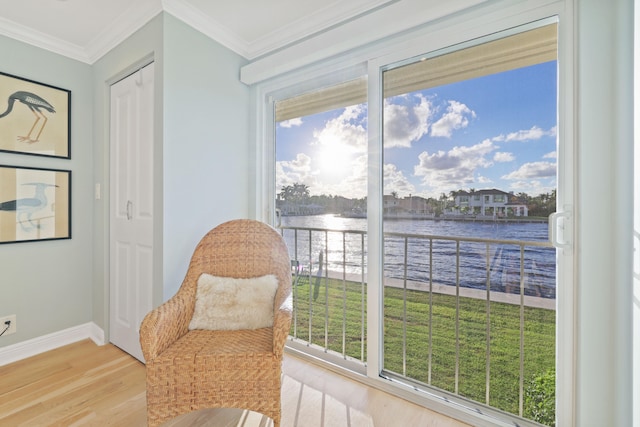 living area with crown molding, a water view, and light hardwood / wood-style floors