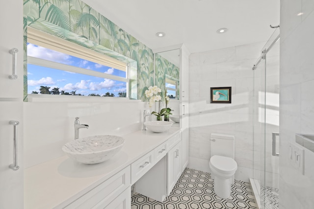 bathroom with toilet, tile patterned floors, a shower with door, vanity, and tile walls