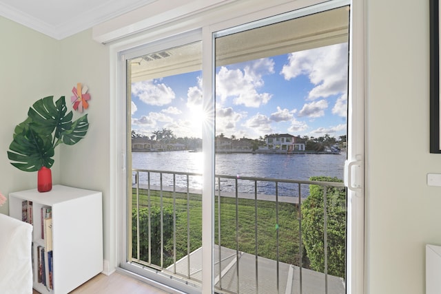 doorway to outside with a water view, light hardwood / wood-style floors, and crown molding