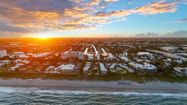 aerial view at dusk with a water view and a beach view