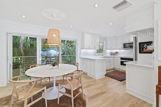 kitchen featuring light hardwood / wood-style flooring, stainless steel appliances, white cabinetry, and tasteful backsplash