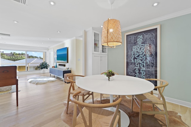 dining area with ornamental molding and light hardwood / wood-style floors