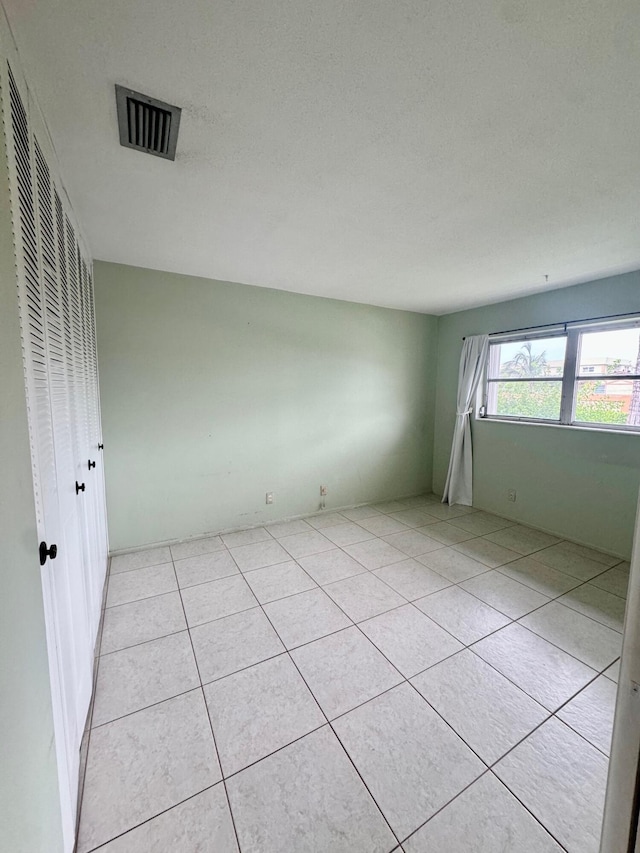 tiled spare room featuring a textured ceiling