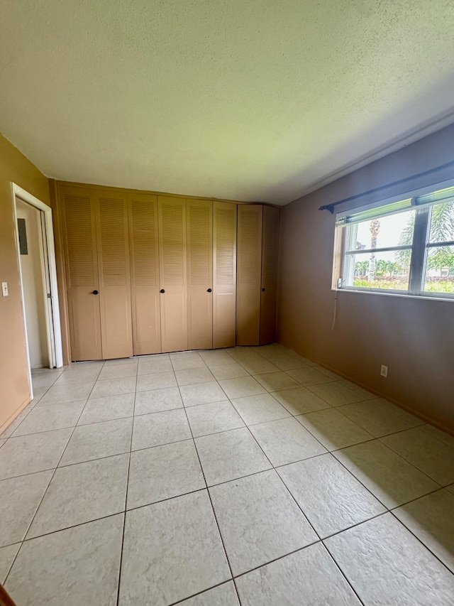 empty room with a textured ceiling and light tile patterned flooring