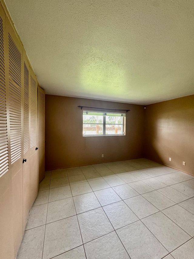 tiled spare room with a textured ceiling