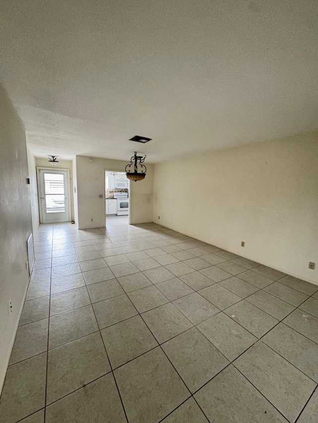 tiled empty room with a textured ceiling