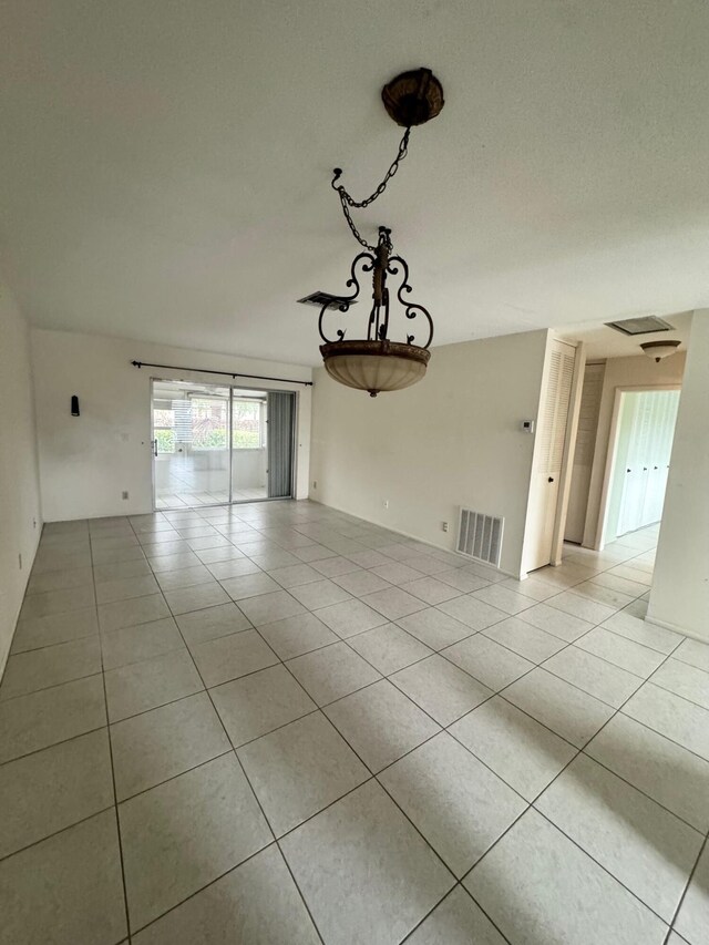 unfurnished room with a textured ceiling and light tile patterned flooring