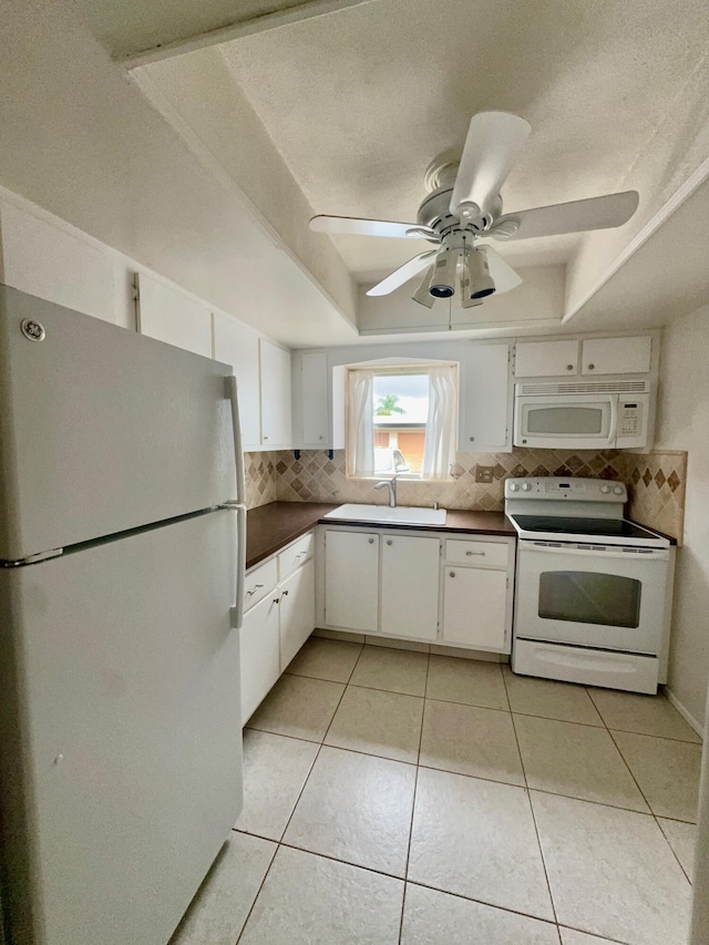 kitchen with white appliances, a raised ceiling, light tile patterned flooring, ceiling fan, and tasteful backsplash