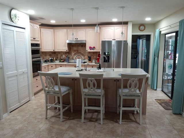 kitchen with tasteful backsplash, under cabinet range hood, light countertops, stainless steel appliances, and a sink