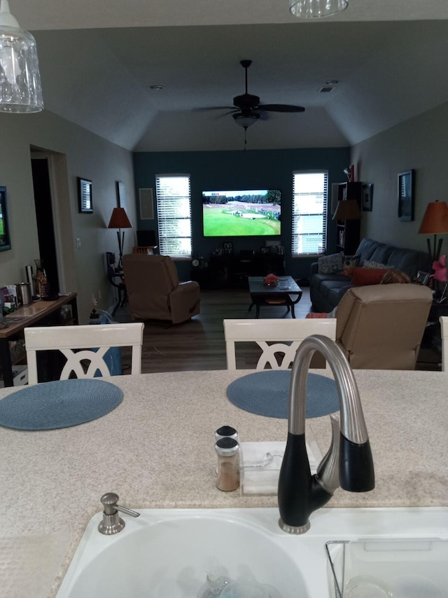 interior space with open floor plan, visible vents, a ceiling fan, and lofted ceiling