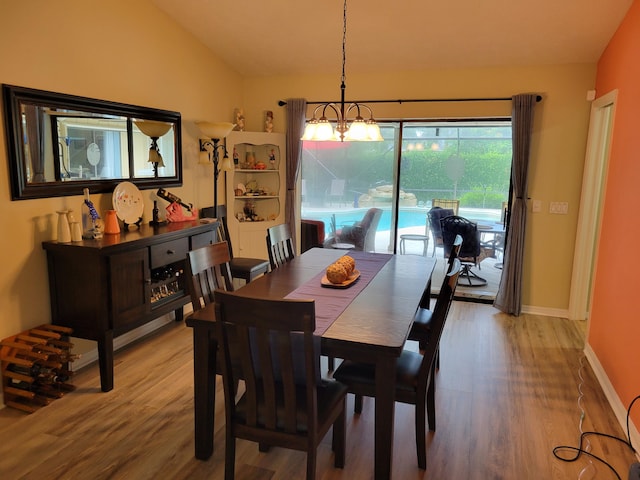 dining space featuring light wood-type flooring, baseboards, a notable chandelier, and vaulted ceiling