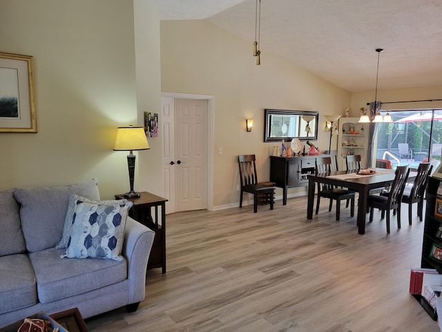 dining space featuring light hardwood / wood-style flooring, high vaulted ceiling, a textured ceiling, and a notable chandelier