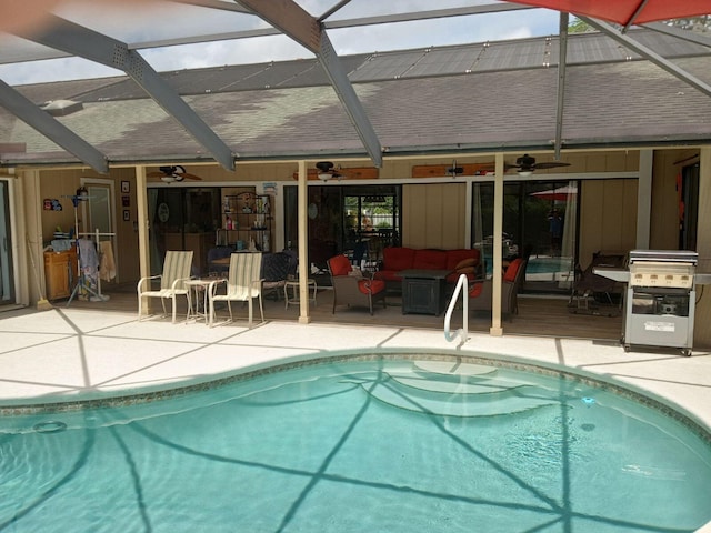 pool with outdoor lounge area, a patio, glass enclosure, and ceiling fan