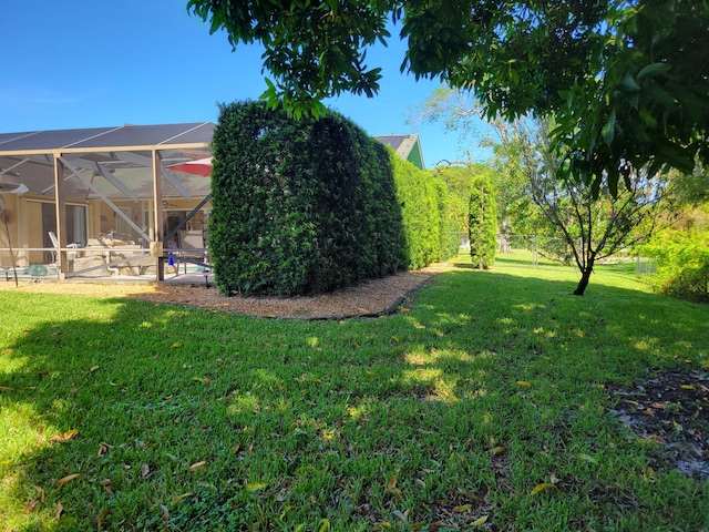 view of yard with glass enclosure and fence